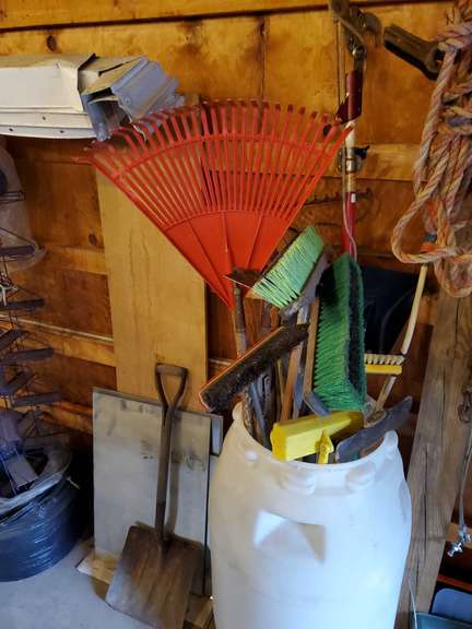 Plastic container with rakes, push brooms, limb loppers, pitchforks ...