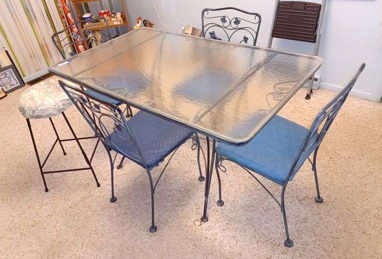 Glass top wrought iron patio table with four chairs, and a metal stool