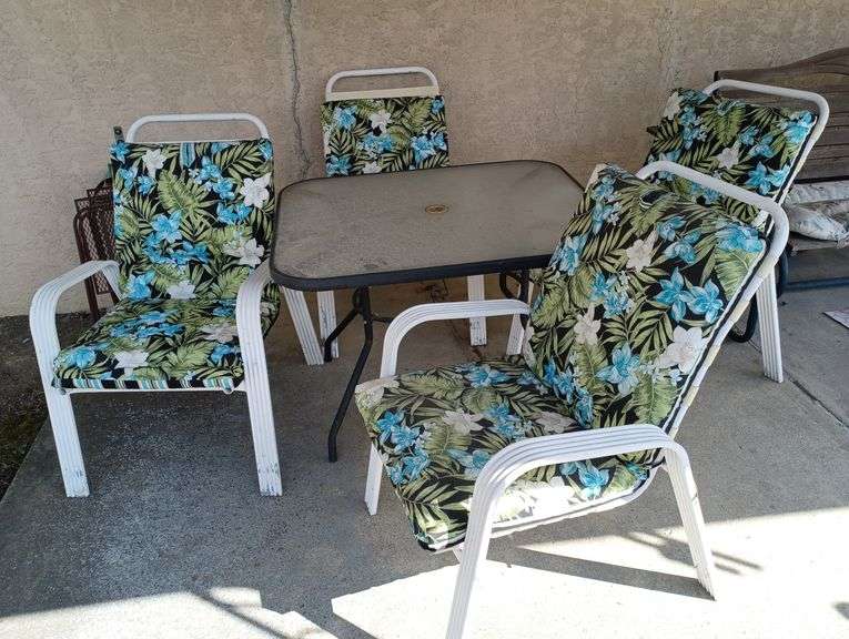 Glass top patio table and four aluminum chairs with cushions, two