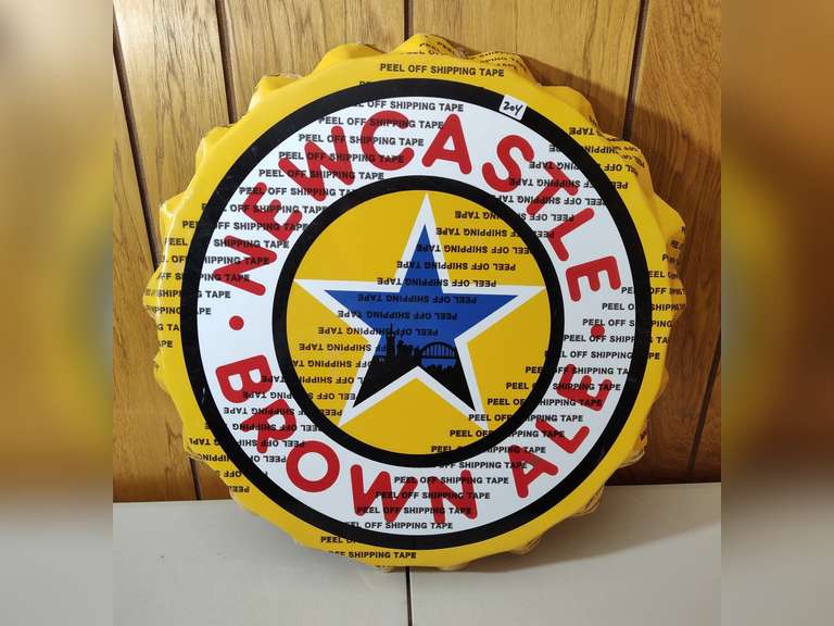 Newcastle Brown Ale metal bottle cap sign still has the plastic on it